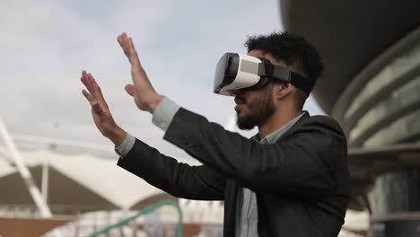 Smiling-middle-eastern-man-using-virtual-reality-headset-outdoor